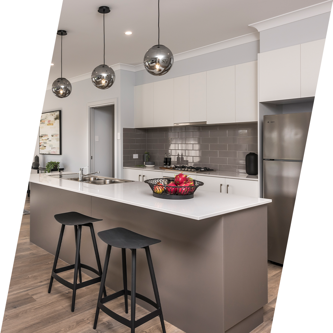 Modern kitchen featuring a large island bench, glossy grey subway tile splashback, white cabinetry, timber-look flooring and pendant lighting.
