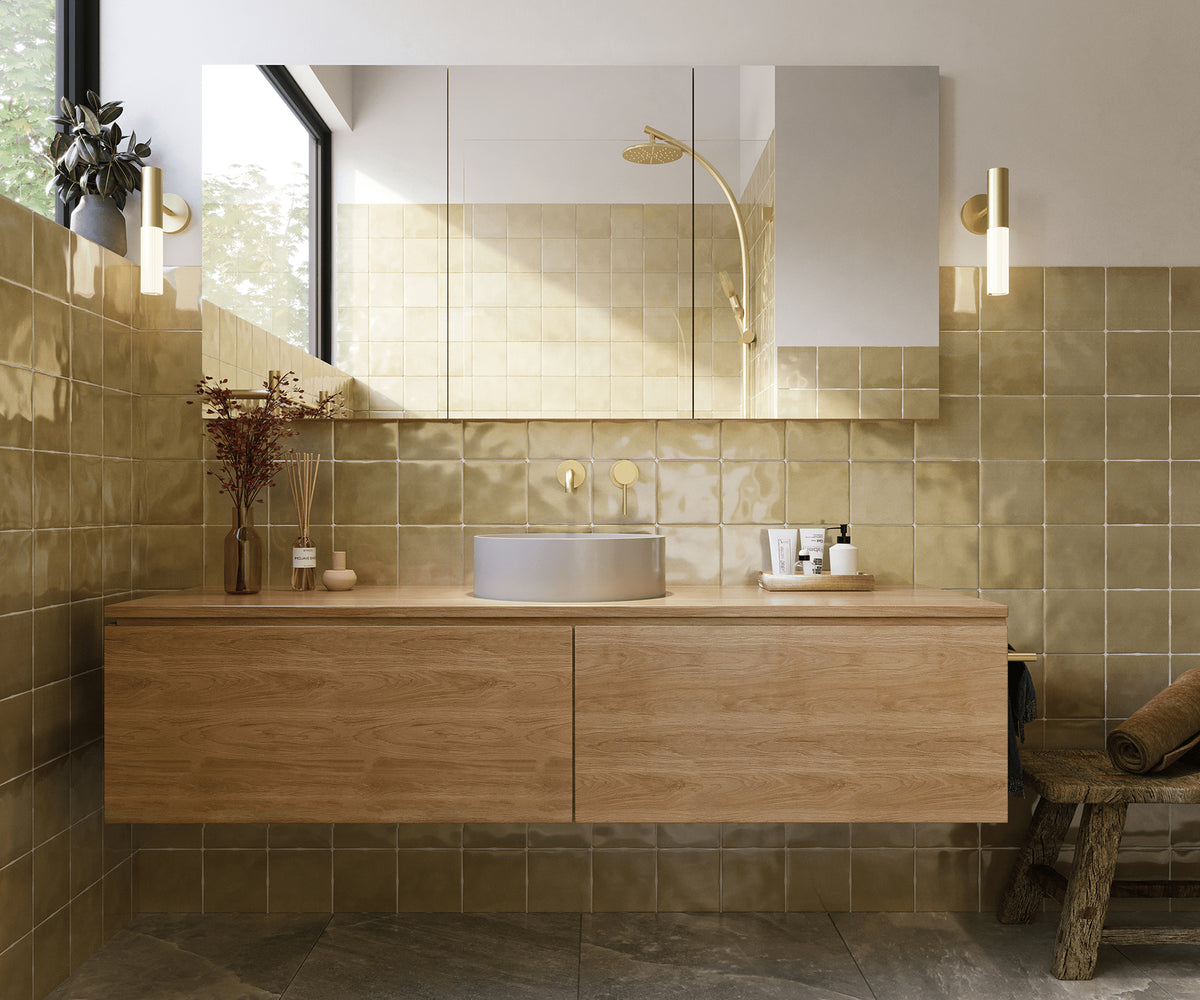 Contemporary bathroom featuring glossy olive-green wall tiles, a floating timber vanity, a round vessel basin, brushed brass tapware and a mirrored shaving cabinet.