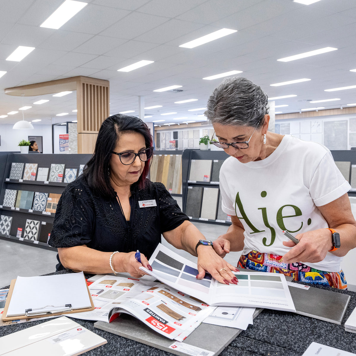 Customer reviewing tile colour samples and product catalogues with a Beaumont Tiles design consultant in-store to help select finishes for a renovation project.