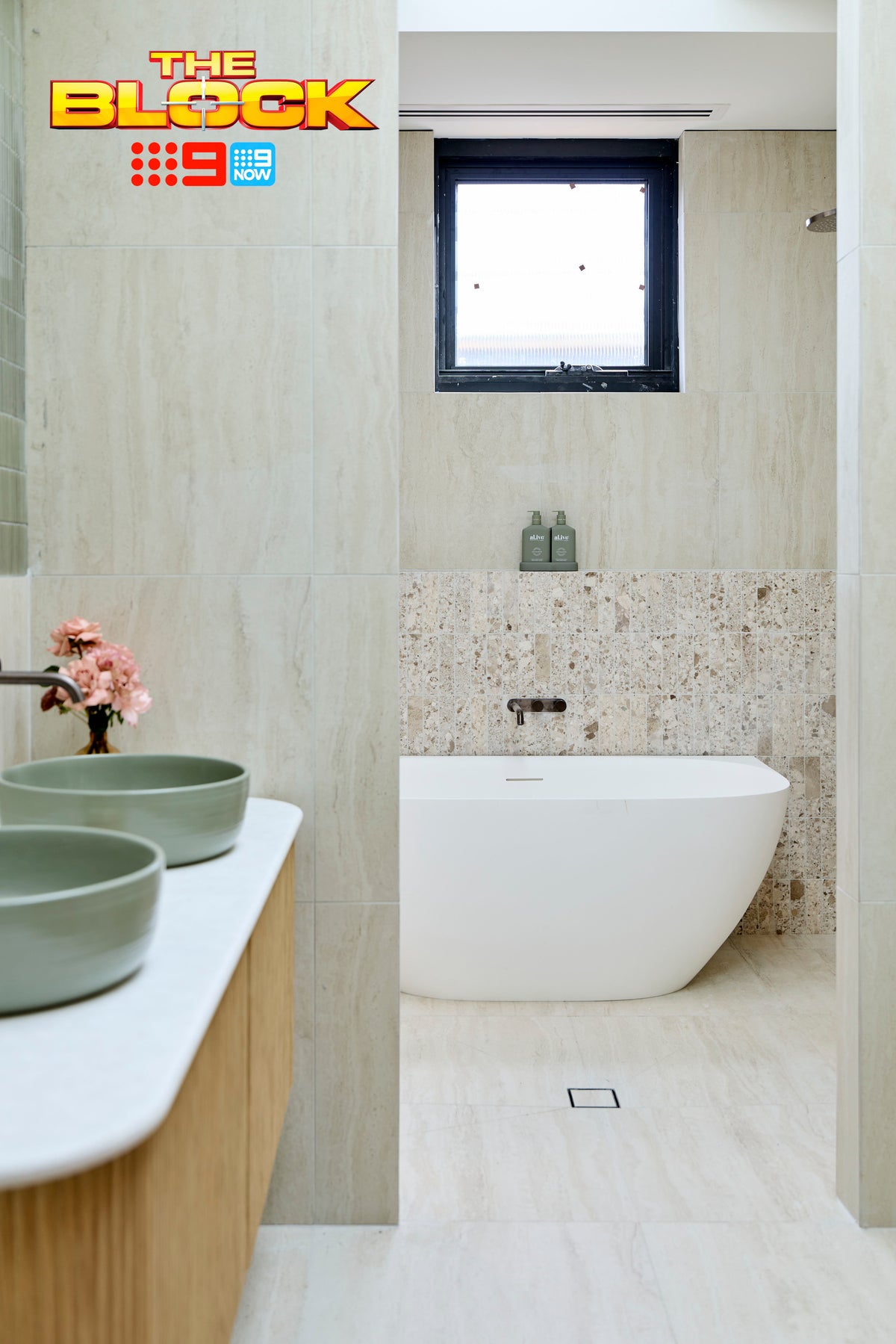 The Block House 1 main ensuite featuring a freestanding white bath, terrazzo-look feature wall tiles, large-format stone-look wall and floor tiles, sage green vessel basins on a floating timber vanity, and a soft neutral palette for a calming spa-inspired bathroom.
