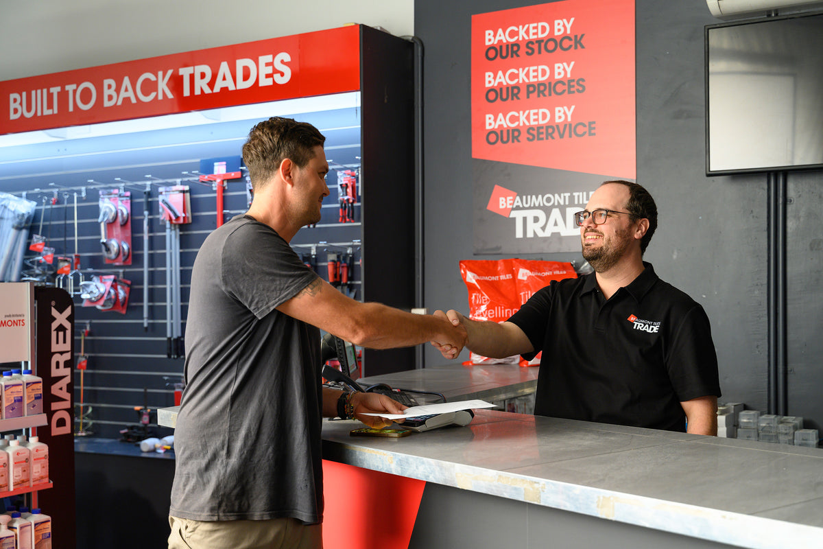 Trade customer and Beaumont Tiles Trade team member shaking hands at the trade counter, highlighting trusted service, expert support and strong trade partnerships.