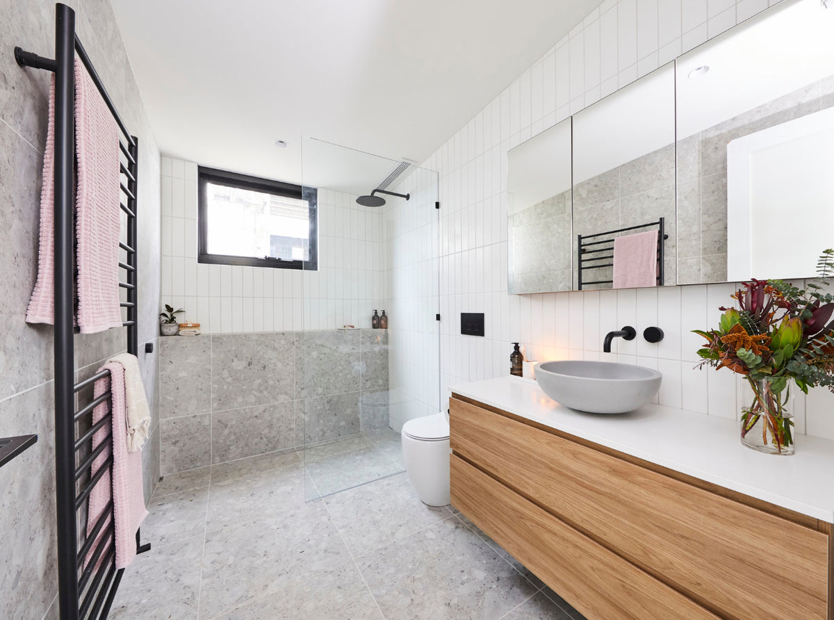 Modern bathroom with a frameless glass shower, natural stone-look tiles, timber vanity and ceiling ventilation system.