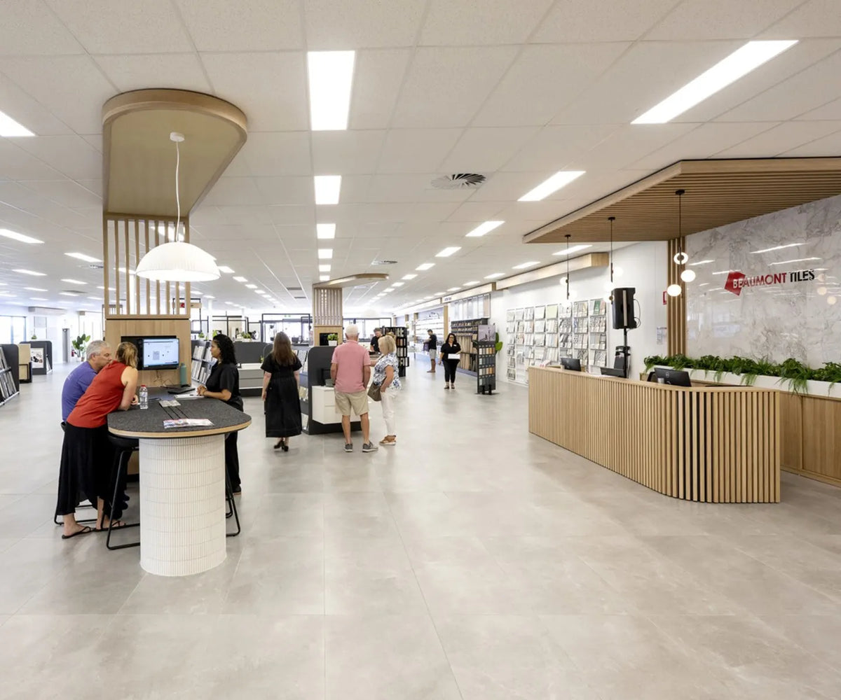 Customers exploring tile displays and receiving expert advice inside a modern Beaumont Tiles showroom featuring consultation areas, product displays and a welcoming reception desk.