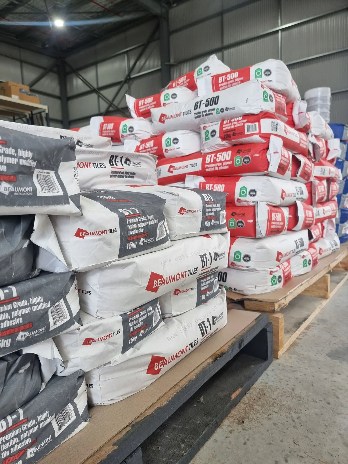 Stacks of Beaumont Tiles BT-500 premium tile adhesive bags stored on pallets in a warehouse, ready for trade and installation projects.