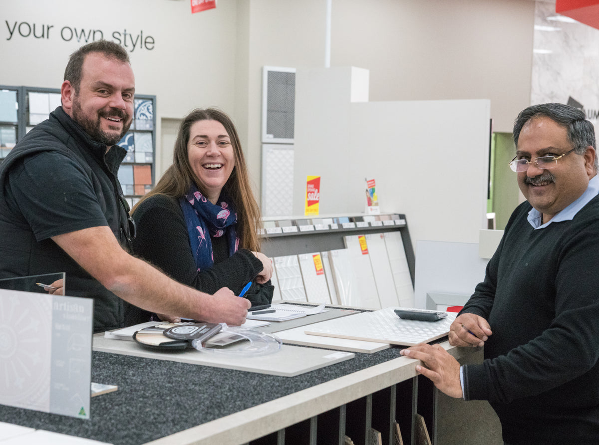 Customers receiving expert advice from a Beaumont Tiles consultant while comparing tile samples and planning a renovation project in a showroom consultation area.