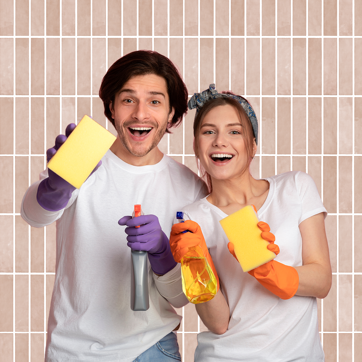 People cleaning a tiled wall while holding sponges and spray bottles, demonstrating tile and grout cleaning in a bathroom setting with blush pink wall tiles.