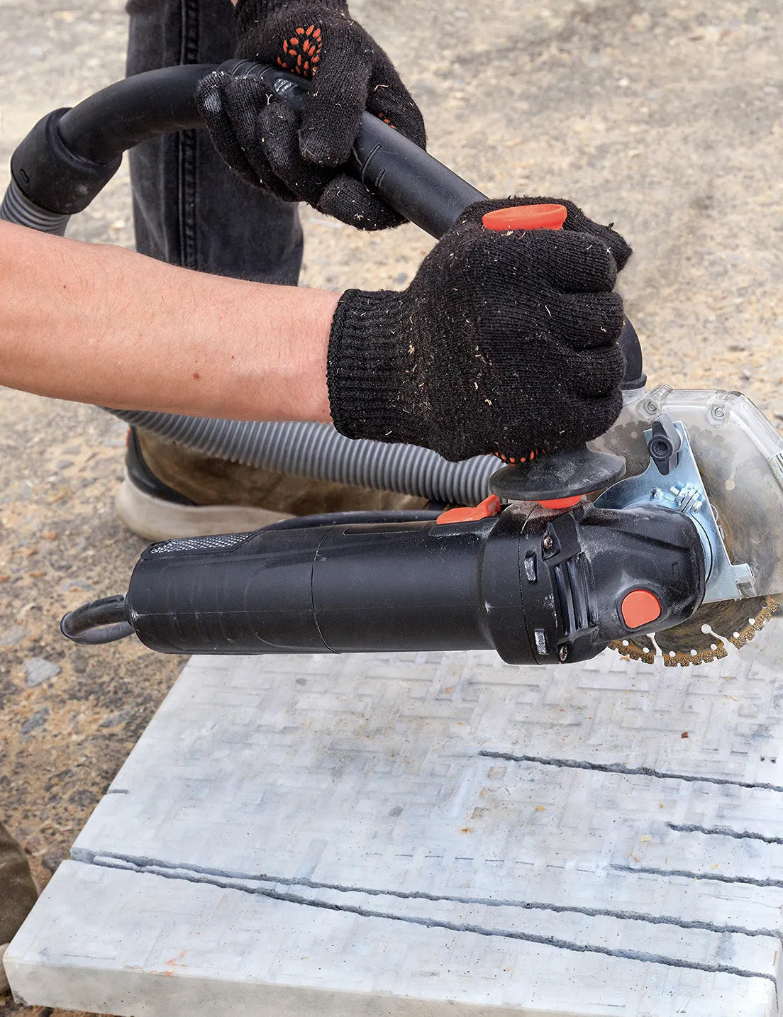 Using an angle grinder to cut a porcelain paver during outdoor tiling and paving installation.